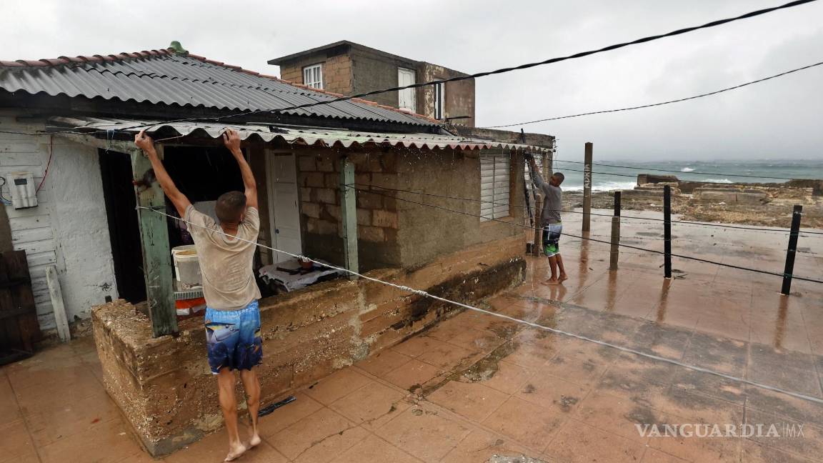 $!Personas amarran las tejas del techo de una casa debido al paso del huracán Rafael en La Habana, Cuba.