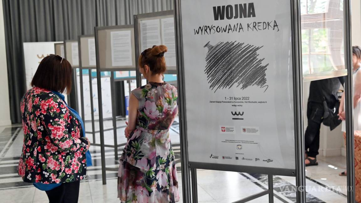 $!Personas miran los dibujos hechos por niños ucranianos en la exposición titulada ‘Guerra dibujada con un crayón’.