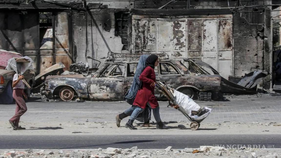 $!Palestinos desplazados internamente caminan cerca de vehículos y edificios destruidos en Khan Yunis, sur de la Franja de Gaza, el 19 de septiembre de 2024.