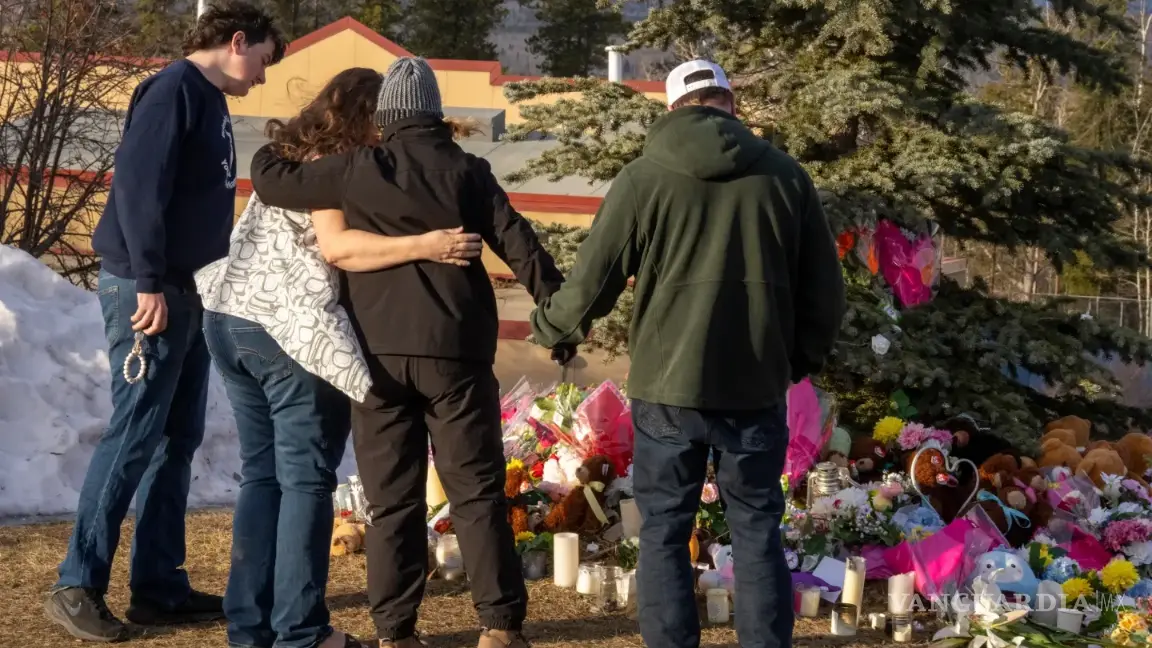 $!Residentes se abrazan mientras depositan flores en un monumento en memoria de las víctimas del tiroteo masivo en Tumbler Ridge, Columbia Británica, Canadá.