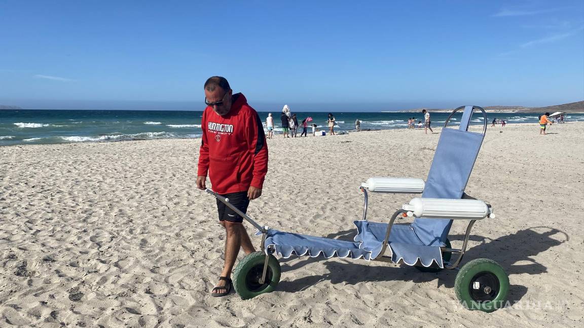$!El experto en mecánica automotriz, Andrés Mata, posa junto a una silla de ruedas anfibia en una playa del balneario de La Paz (México).