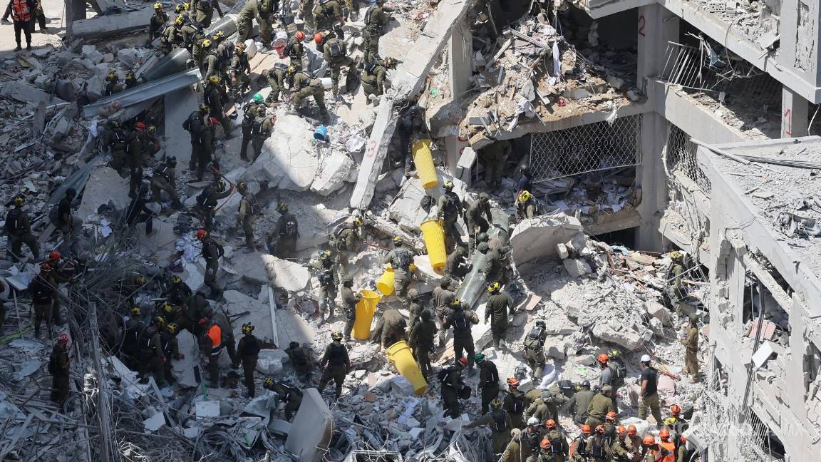 $!Miembros del Comando del Frente Interno de Israel buscan a personas desaparecidas bajo los escombros de un edificio residencial en Bat Yam.