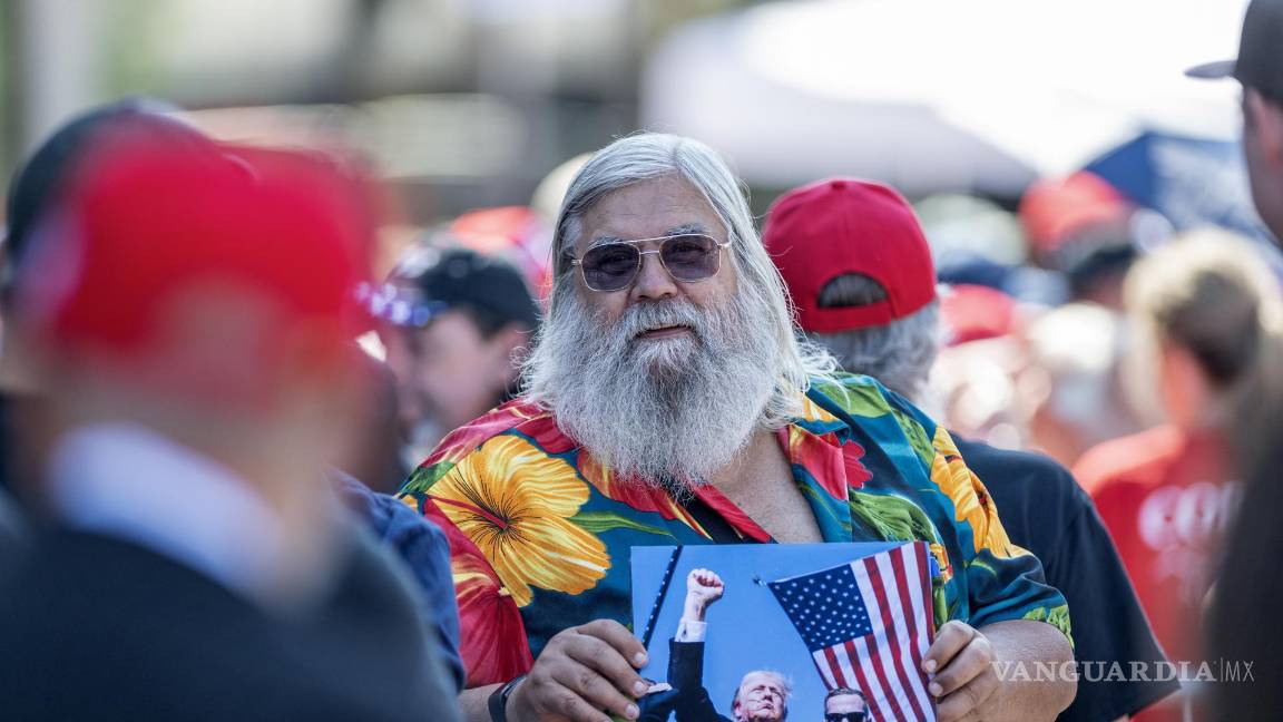 $!Un partidario sostiene una fotografía de Donald Trump mientras espera el inicio de un acto de campaña del candidato presidencial republicano en Asheville.