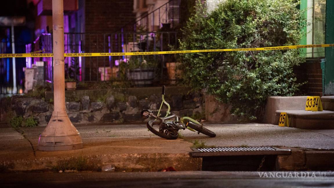 $!Una bicicleta perteneciente a una de las víctimas, un niño que sobrevivió a los disparos en la pierna, yace en la escena de un tiroteo en Kingsessing, Pensilvania.