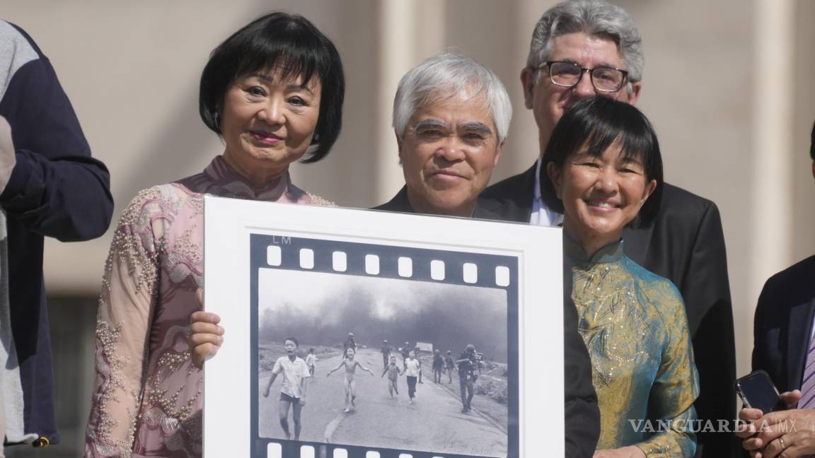 $!El fotógrafo ganador del Premio Pulitzer Nick Ut (c), flanqueado por Kim Phuc (i) sostiene la “Niña del napalm” en la Plaza de San Pedro en el Vaticano.