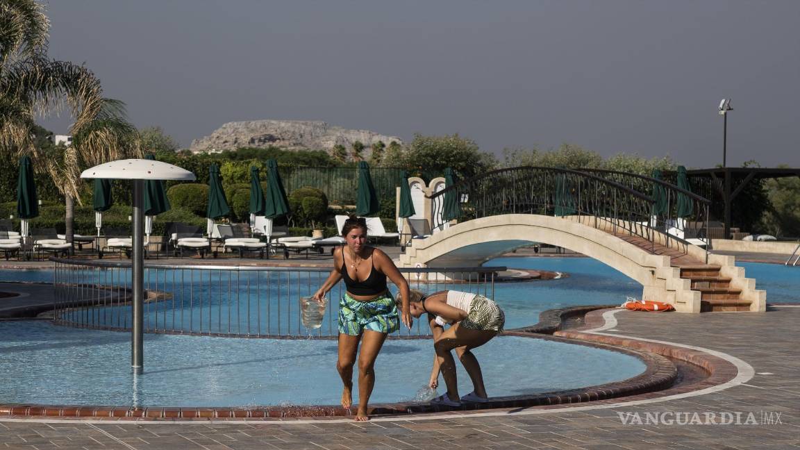 $!Turistas alemanes y vecinos intentan extinguir un incendio cerca del balneario de Lindos, en la isla griega de Rodas en el mar Egeo.