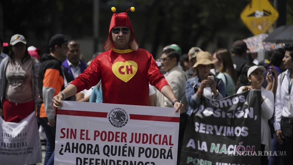 $!El trabajador judicial Jorge Reyes, vestido como el Chapulín Colorado, con un cartel que dice: “Sin poder judicial, ¿quién podrá defendernos ahora?” afuera del Senado.