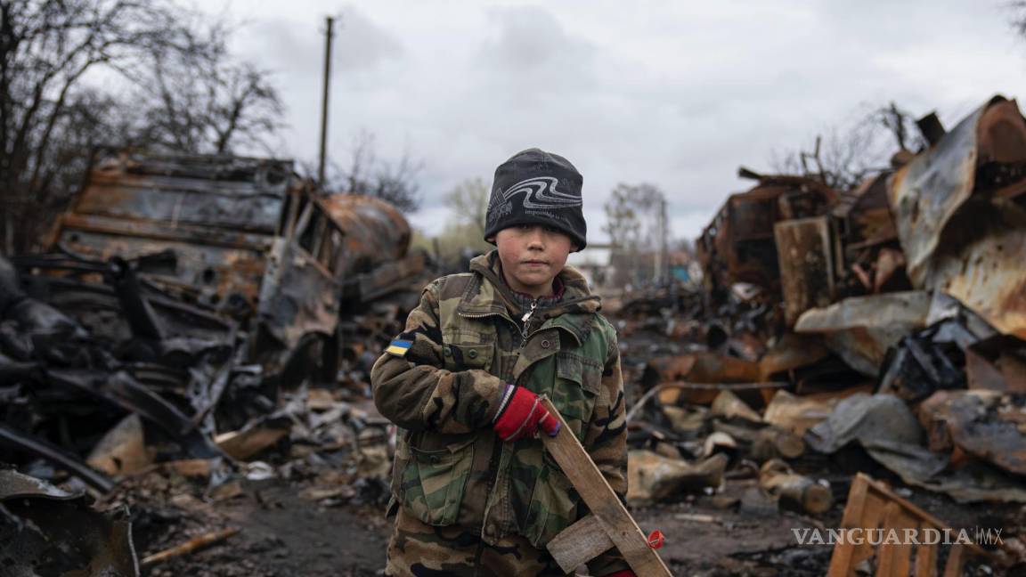 $!Yehor, de 7 años, sostiene un rifle de juguete junto a vehículos militares rusos destruidos, cerca de Cherníhiv, Ucrania, el 17 de abril de 2022.