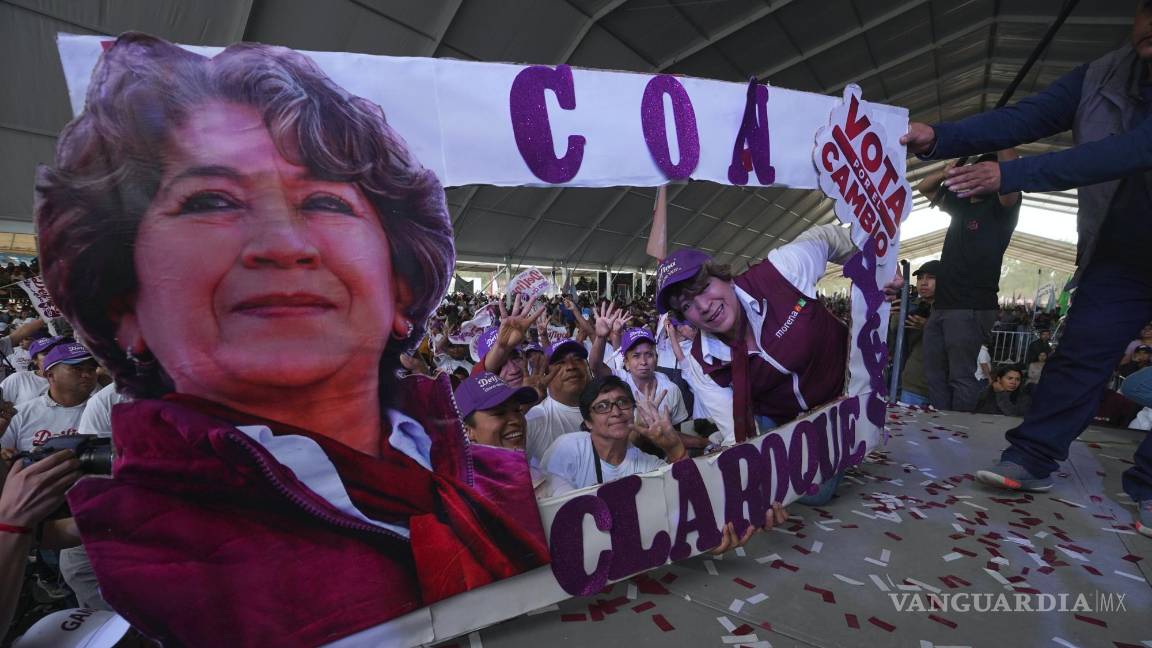 $!Delfina Gómez, candidata del partido Morena a la gubernatura del Estado de México posa junto a una pancarta con su imagen en un evento de campaña.