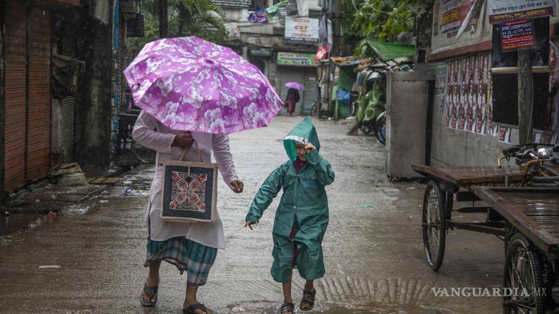 $!La gente camina por la calle durante las fuertes lluvias mientras el ciclón Midili afecta la zona costera de Dhaka, Bangladesh.