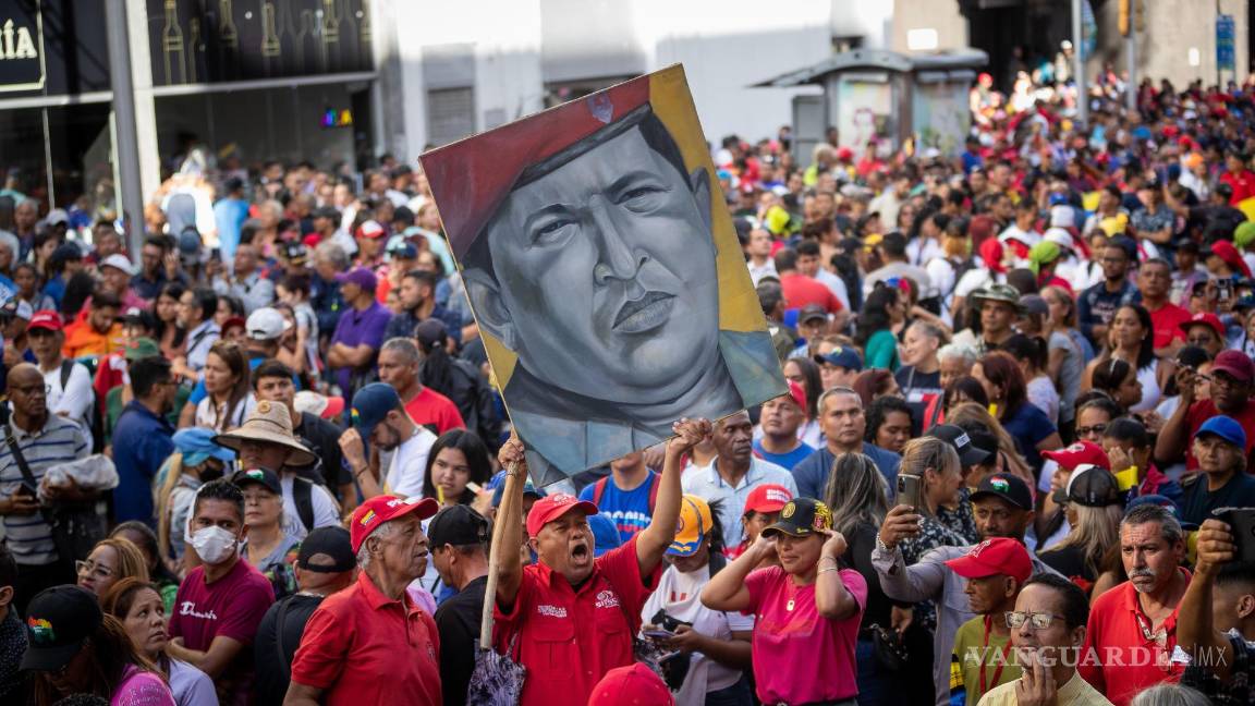 $!Un hombre carga un cuadro con la imagen del expresidente fallecido Hugo Chávez durante una marcha adepta al gobierno de Nicolás Maduro en Caracas, Venezuela.