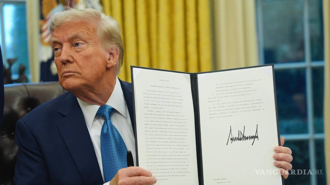 $!El presidente Donald Trump sostiene una orden ejecutiva firmada sobre desregulación en la Oficina Oval de la Casa Blanca en Washington.