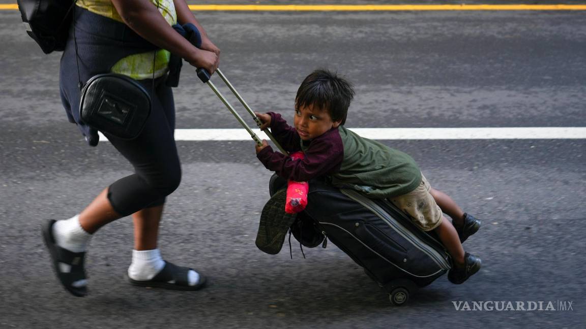 $!Nayely Núñez, de Honduras, utiliza su maleta como carro para mover a un niño mientras camina junto a una caravana de migrantes por una carretera en Huixtla.