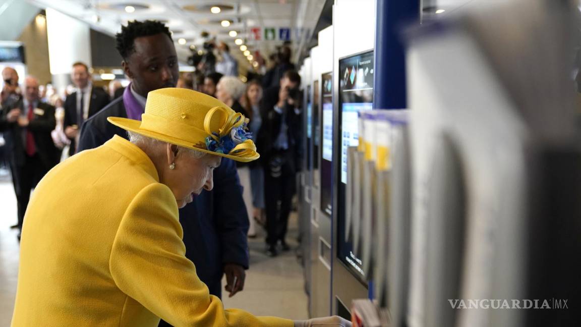 $!La reina Isabel II de Gran Bretaña usa una máquina de tarjetas en la estación de Paddington en Londres.