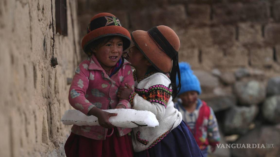 $!Niñas juegan con un bloque de hielo formado por aguanieve que cayó el día anterior sobre la comunidad de Cconchaccota, en la región Apurímac de Perú.
