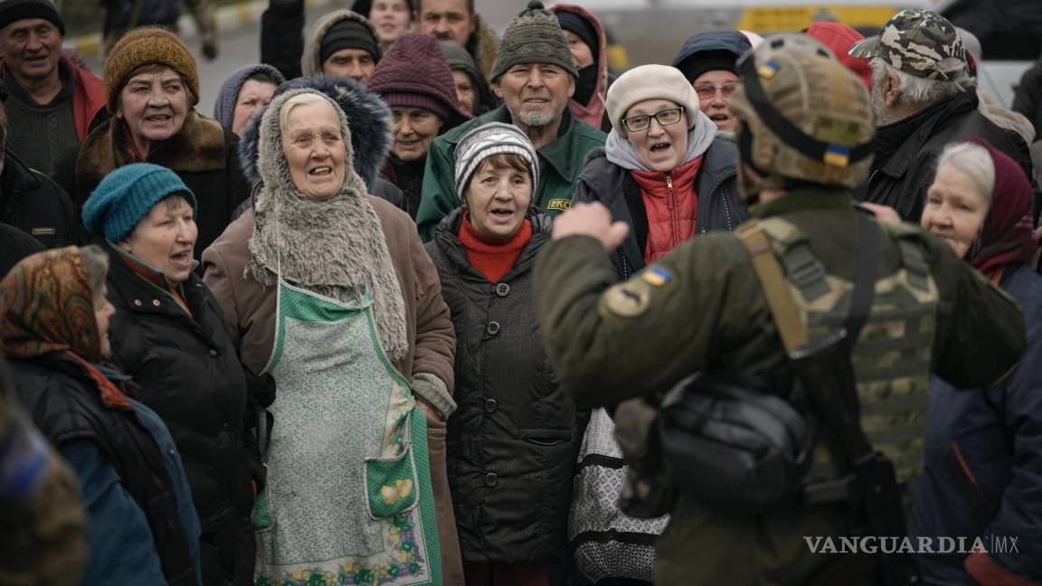 $!Civiles vitoreando junto con un combatiente ucraniano a la llegada de un convoy de vehículos militares y de ayuda a Bucha.