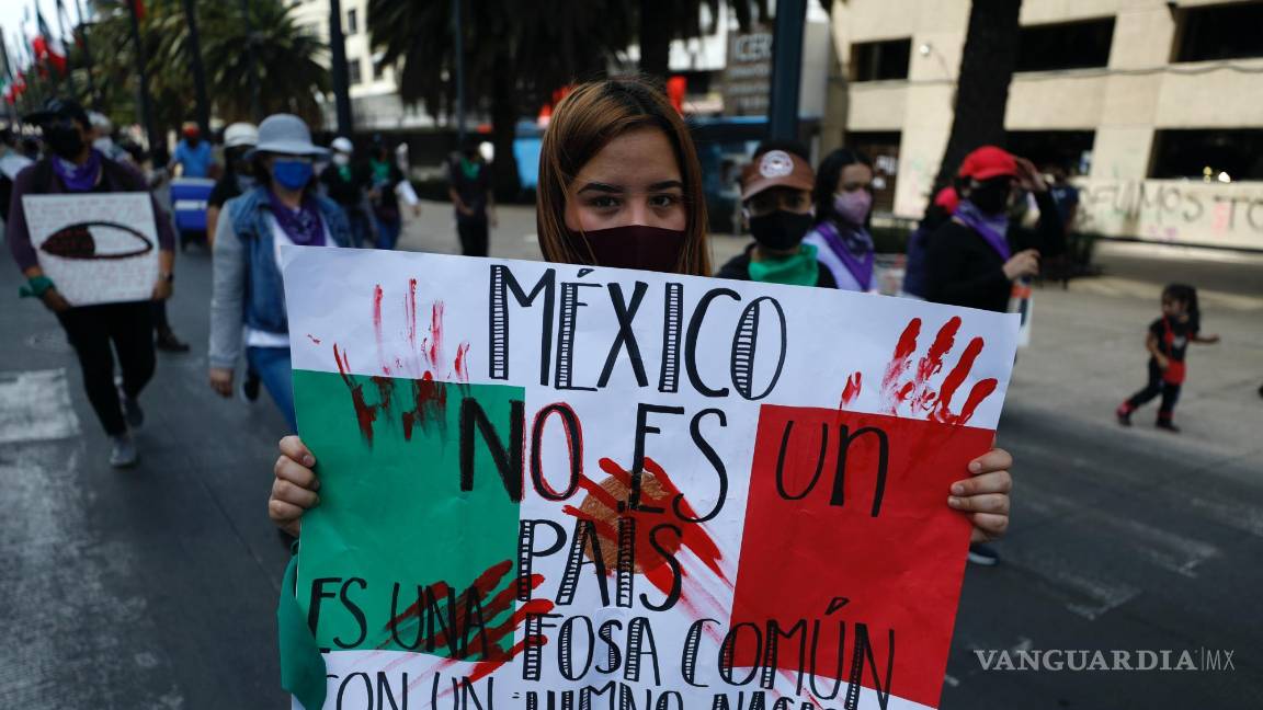 $!8/03/2021. Una manifestante con un cartel con la frase México no es un país, es una fosa común con un himno nacional durante una marcha en CDMX.