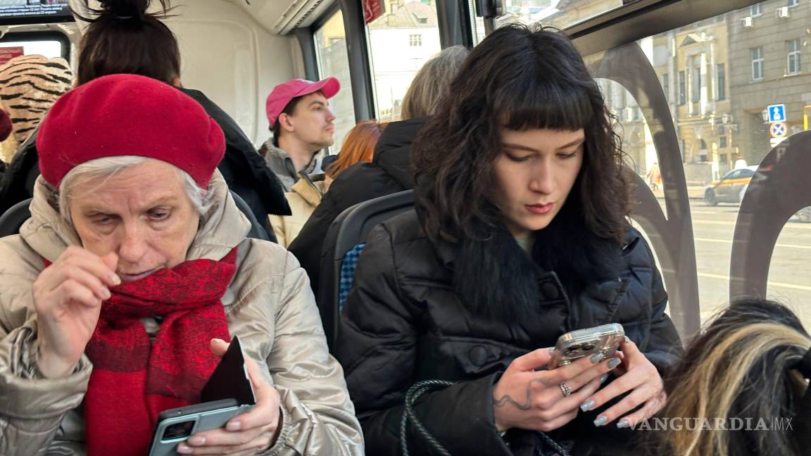 $!Dos mujeres consultan sus celulares durante un viaje en bus en Moscú.