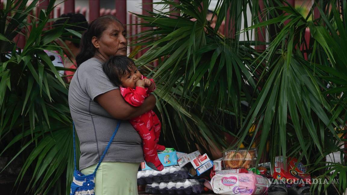 $!Una mujer sostiene a un bebé en brazos junto a varios alimentos tomados de un establecimiento luego del paso del huracán Otis por Acapulco, Guerrero (México).