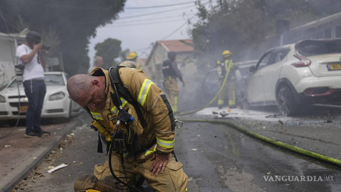 $!Un bombero israelí se arrodilla exhausto después de que él y sus compañeros apagaron vehículos incendiados por los cohetes lanzados desde la Franja de Gaza, el lunes 9 de octubre de 2023, en Ascalón, Israel. (AP Foto/Ohad Zwigenberg)