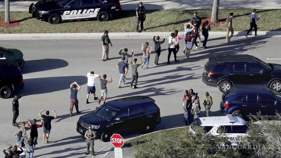 $!Varios estudiantes levantan los brazos mientras son evacuados por la policía de la escuela secundaria Marjory Stoneman Douglas en Parkland, Florida.