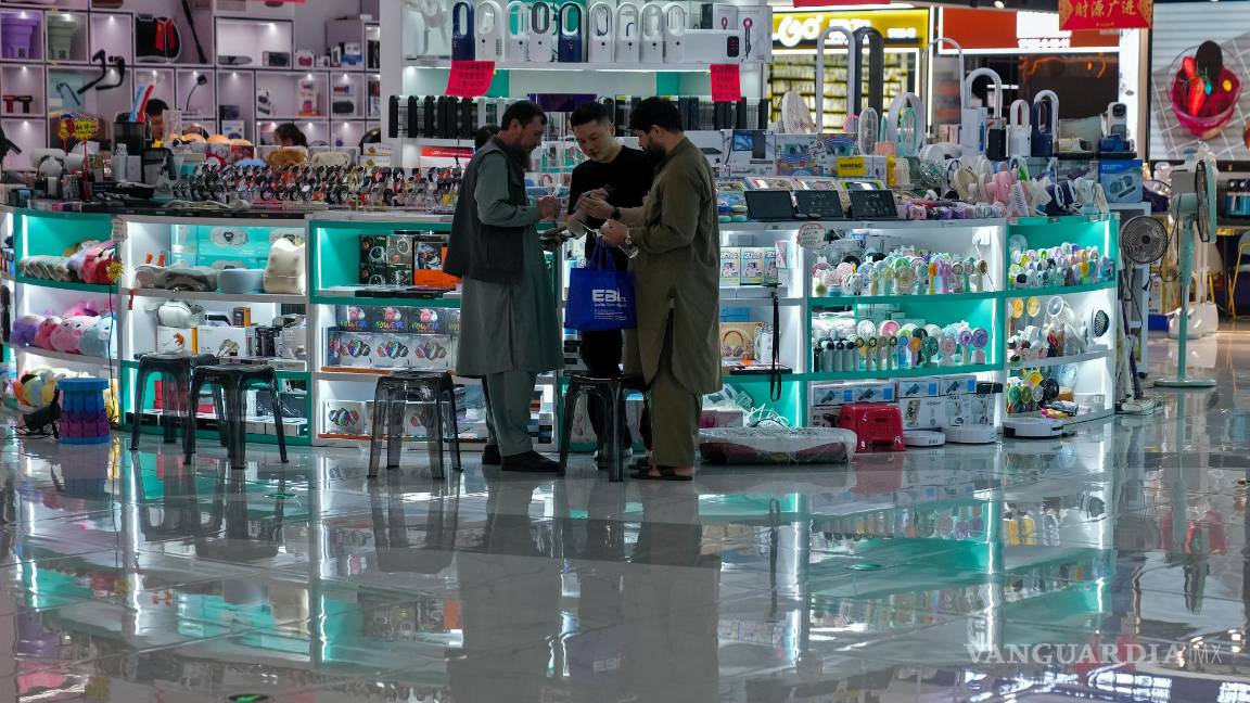 $!Compradores extranjeros consultan precios con un vendedor en una tienda que vende productos electrónicos en el mercado de Yiwu, en Yiwu en China.