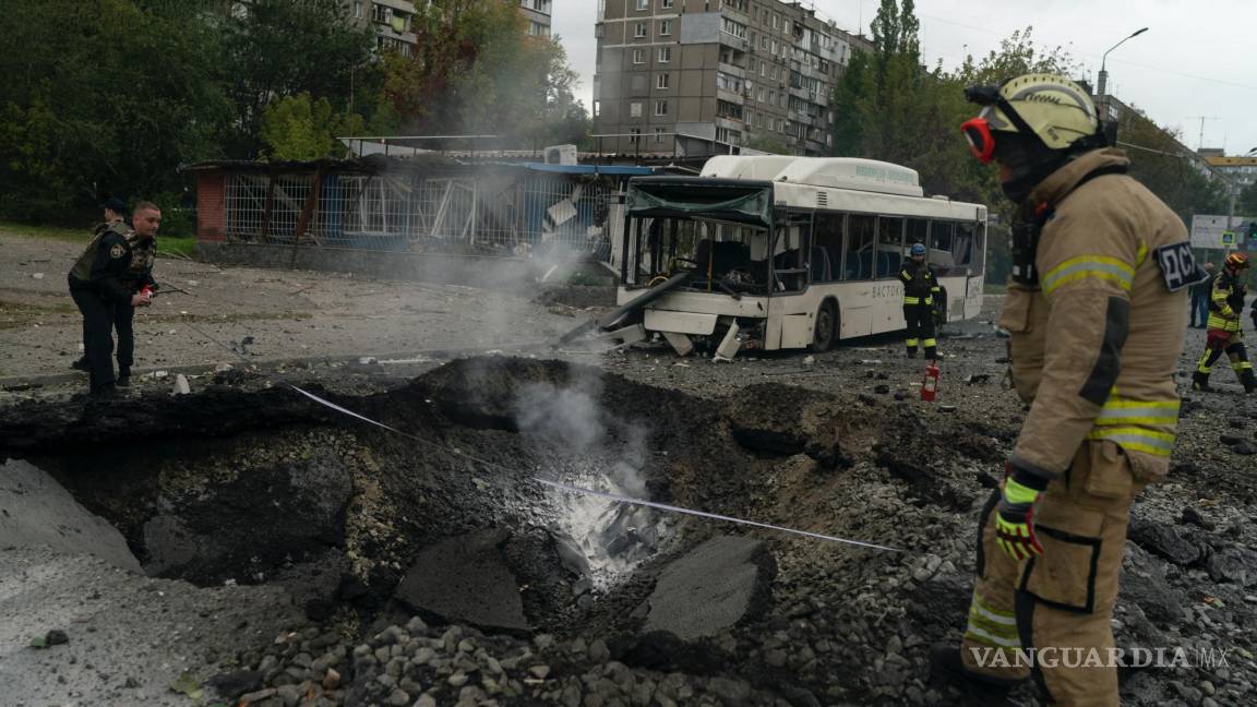 $!Bomberos y policías trabajan en un sitio donde una explosión creó un cráter en la calle después de un ataque ruso en Dnipro, Ucrania.