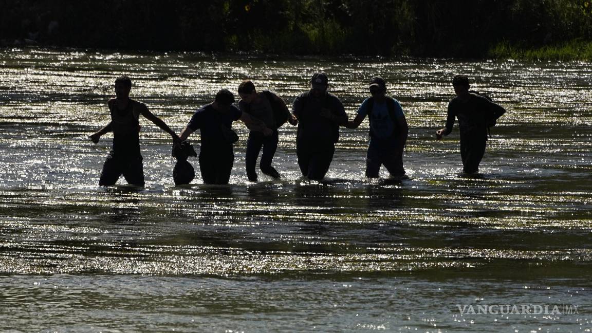 $!Migrantes se toman de las manos mientras cruzan el Río Grande.
