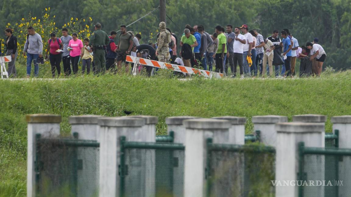 $!Migrantes hablan con agentes en un camino a un costado del río Bravo tras cruzar la frontera entre Texas y México en Brownsville, Texas.