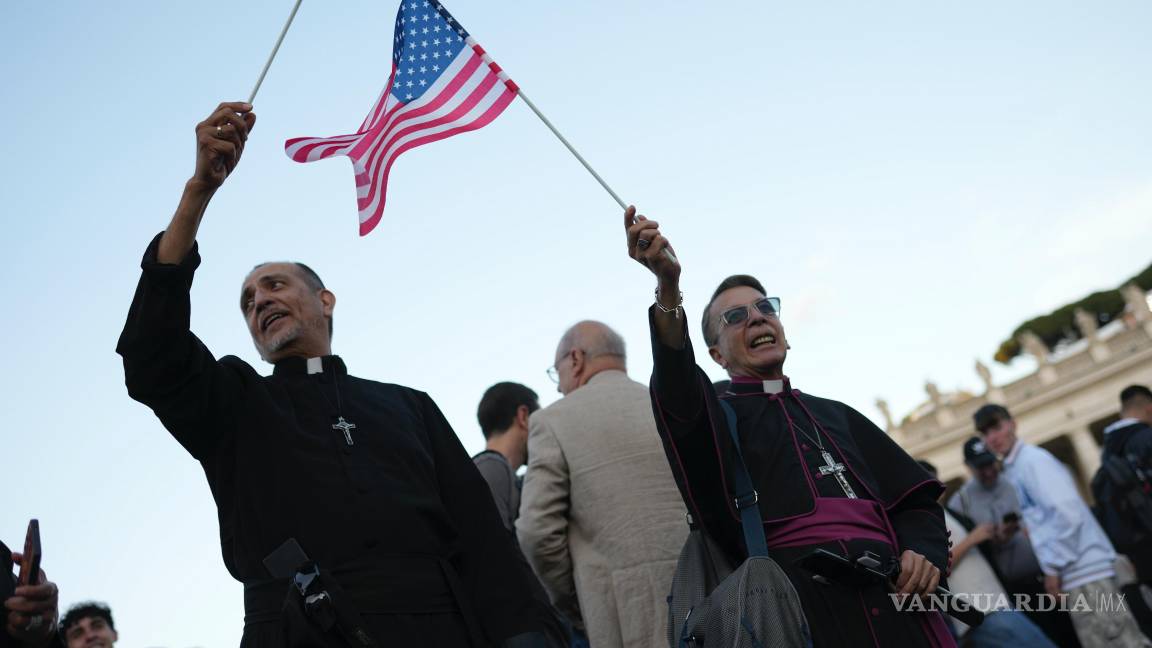 $!Clérigos ondean banderas de Estados Unidos durante el discurso del recién elegido Papa León XIV en el Vaticano.