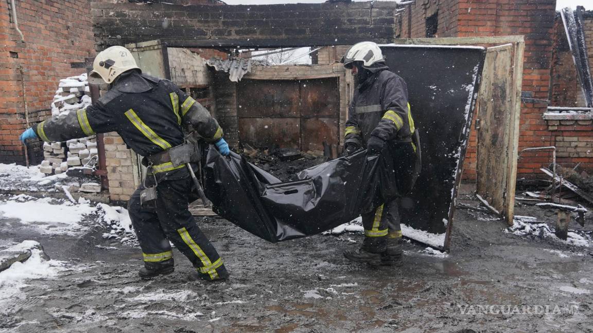 $!Los bomberos transportan el cuerpo de un residente que murió en un incendio cuando un dron ruso impactó su casa en un vecindario residencial en Kharkiv.