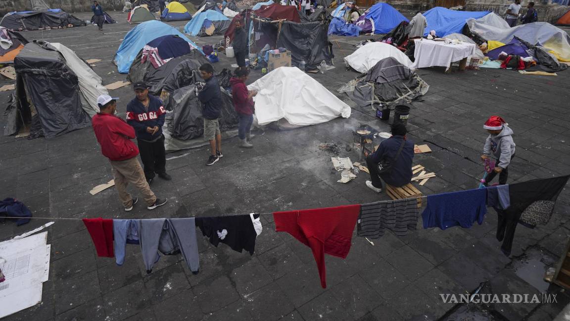 $!Migrantes se reúnen en un campamento instalado en la plaza de la parroquia de Santa Cruz y La Soledad en el barrio de La Merced de Ciudad de México.
