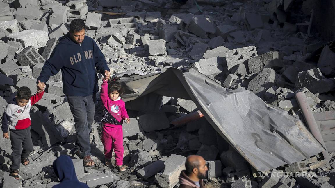 $!Un palestino con dos niños camina entre los escombros de una casa destruida tras los ataques aéreos israelíes en el campo de refugiados de Al Nusairat.