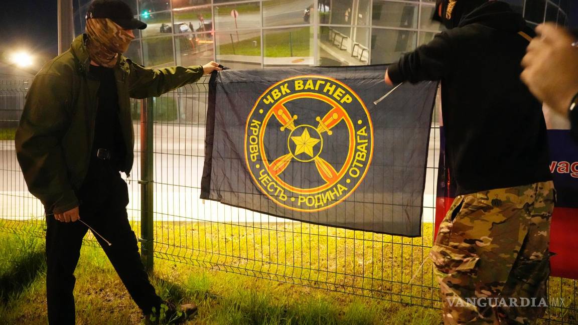 $!Dos personas cuelgan una bandera de ‘PMC Wagner’ en un monumento junto al antiguo ‘Centro PMC Wagner’ en San Petersburgo, Rusia.