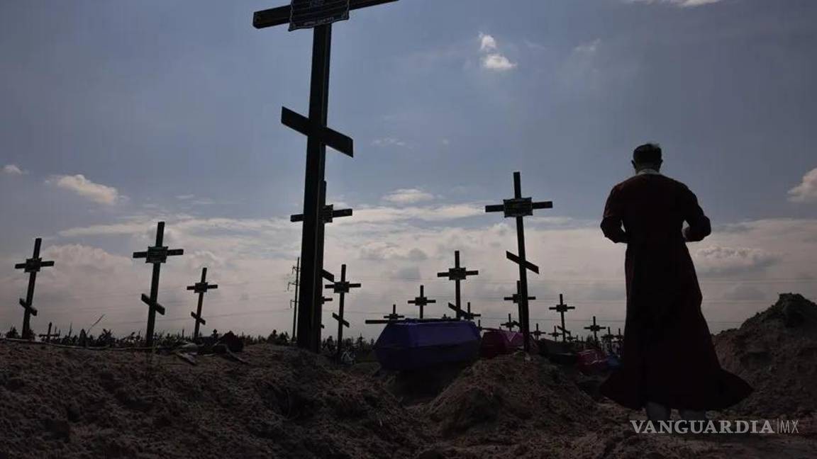 $!En la imagen, un sacerdote ortodoxo ante un a fosa común en Bucha en agosto de 2022.