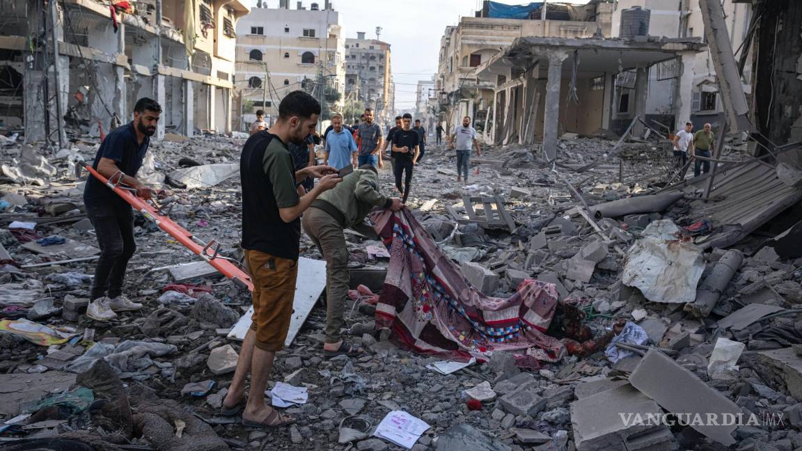 $!Varios palestinos recogen cadáveres de entre los escombros tras un bombardeo israelí en la Ciudad de Gaza.