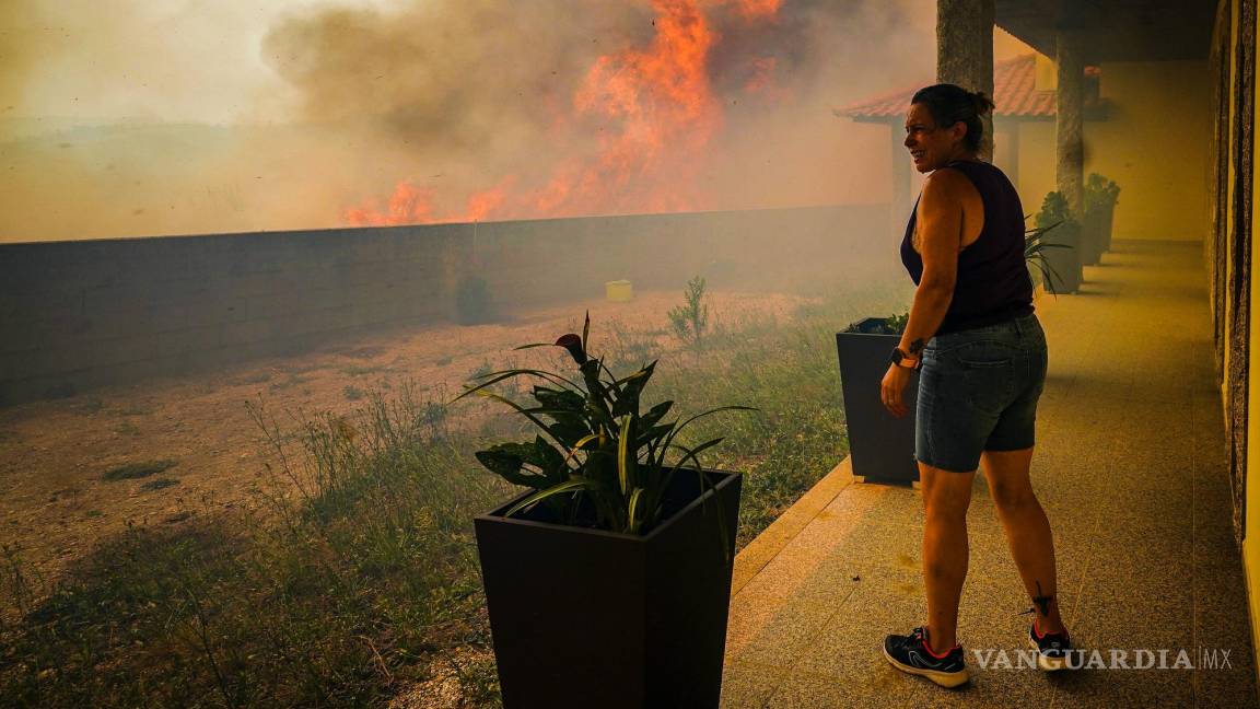 $!Una mujer mira las llamas que queman los árboles que rodean su casa en el pueblo de Ancede en el municipio de Baiao, al norte de Portugal.
