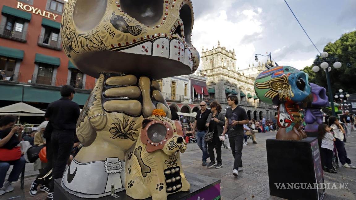 $!Visitantes observan piezas de la exposición Me lleva la huesuda en el zócalo de la ciudad de Puebla (México).