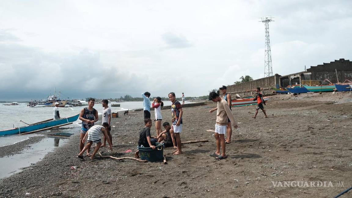 $!Niños y familias regresan a sus hogares un día después de que el supertifón Noru azotara su comunidad pesquera en el pueblo costero de Dinahican, Filipinas.
