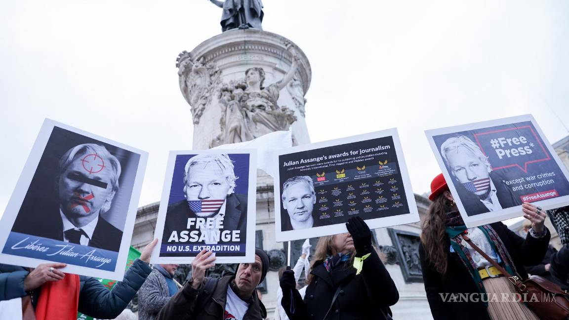 $!Personan sostiene pancartas con retratos de Julian Assange, durante una manifestación para apoyarlo, en la Place de la Republique en París, Francia.