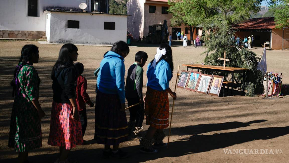 $!Jóvenes indígenas rarámuri caminan hacia un altar donde hay colocados retratos de dos curas jesuitas muertos en Cuiteco, México.