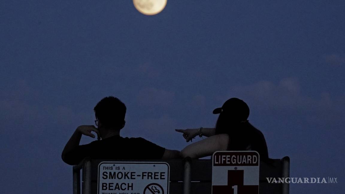 $!La gente observa la luna creciente en East Boston, Massachusetts. Durante el fenómeno conocido como la “Luna de la fresa”.