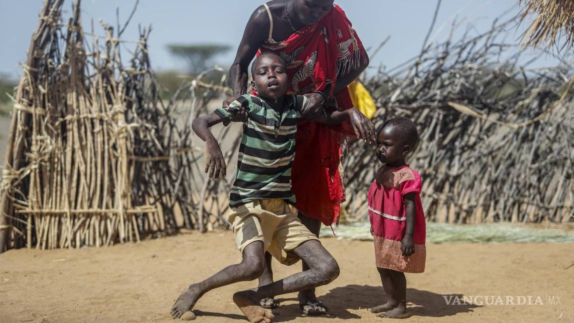 $!Una mujer ayuda a su hijo desnutrido a pararse después que se desmayó cerca de su choza en la aldea de Lomoputh, Kenia.