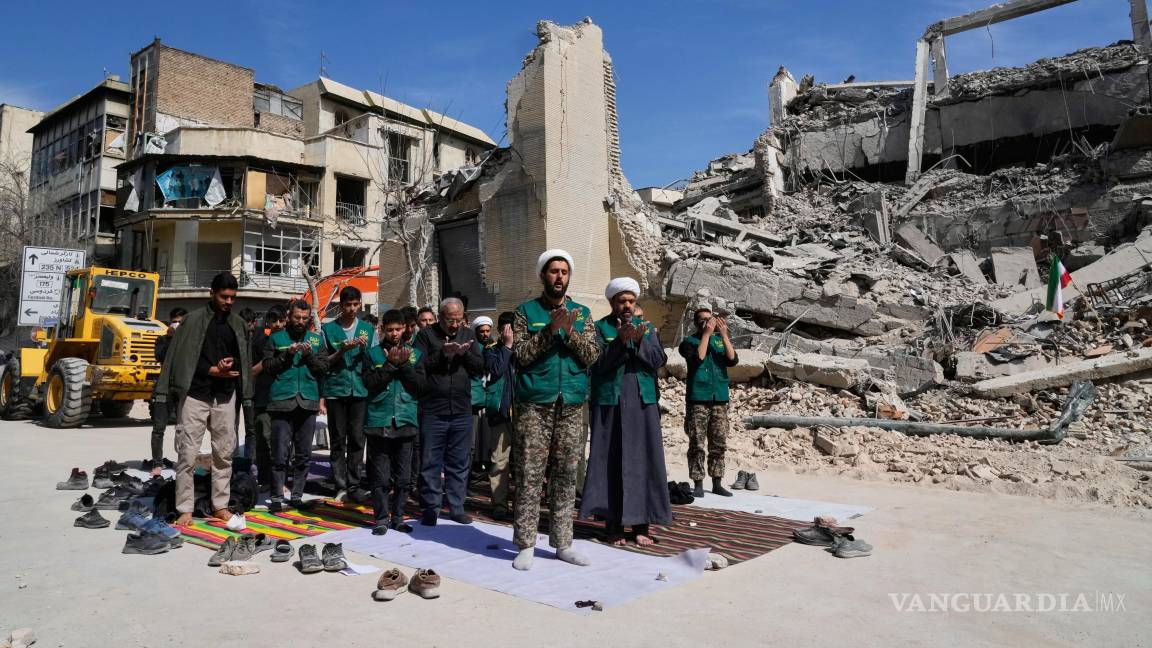 $!Un clérigo guía a un grupo de voluntarios en oración junto a una instalación policial atacada durante la campaña militar estadounidense-israelí en Teherán.