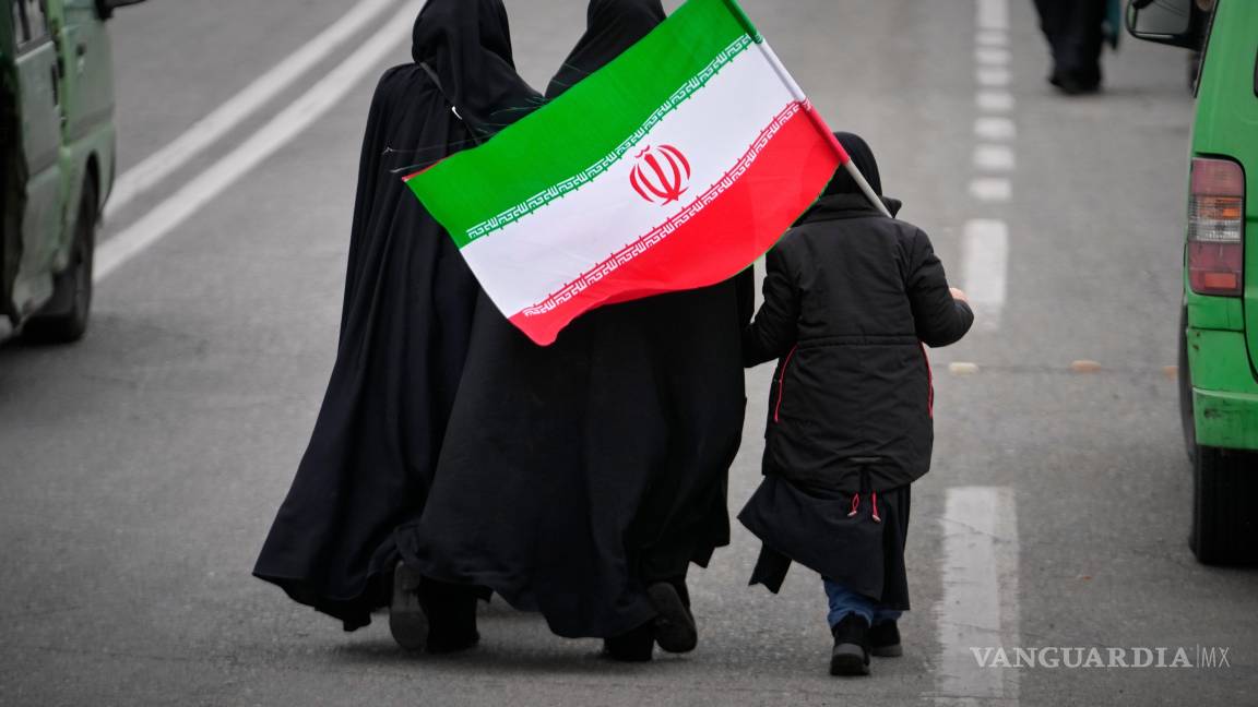 $!Dos mujeres y una menor con una bandera iraní caminan hacia la Gran Mezquita para asistir a las oraciones del viernes en Teherán, Irán.