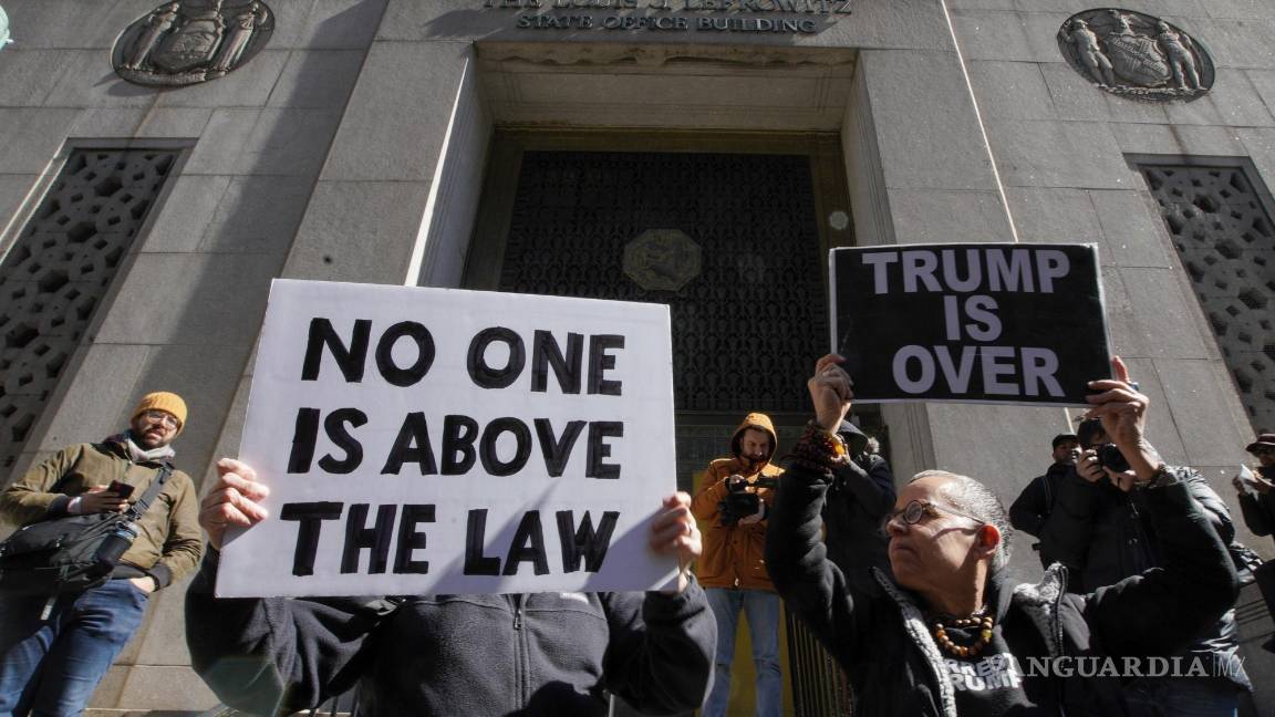 $!Varias personas sostienen carteles que dicen nadie está por encima de la ley y Trump está acabado durante una protesta el lunes 20 de marzo de 2023 frente a la corte donde será encausado el expresidente.