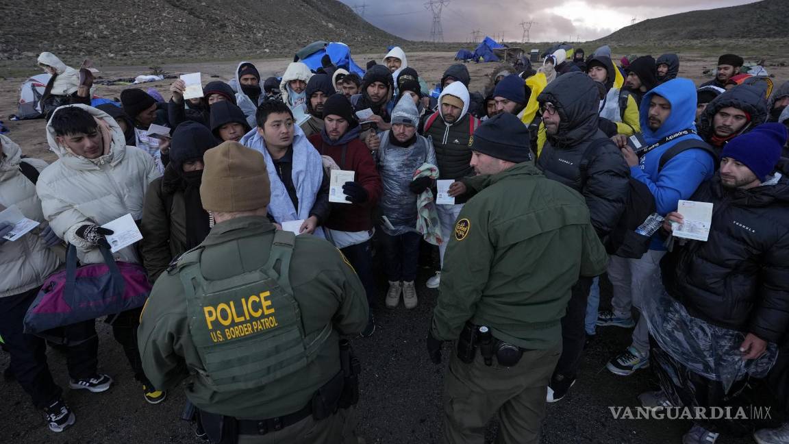 $!Agentes de la Patrulla Fronteriza hablan con migrantes que buscan asilo en un campamento improvisado después de cruzar la frontera con México.