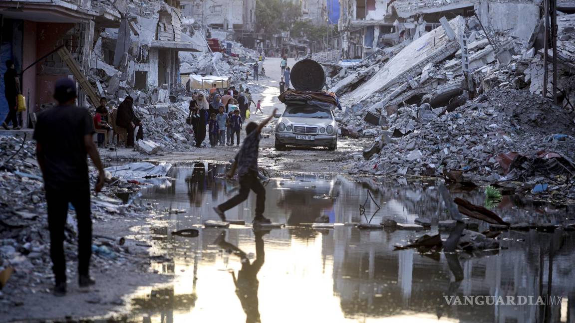 $!Palestinos desplazados por la ofensiva terrestre y aérea de Israel en la Franja de Gaza caminan cerca de aguas residuales en las calles del poblado de Jan Yunis.