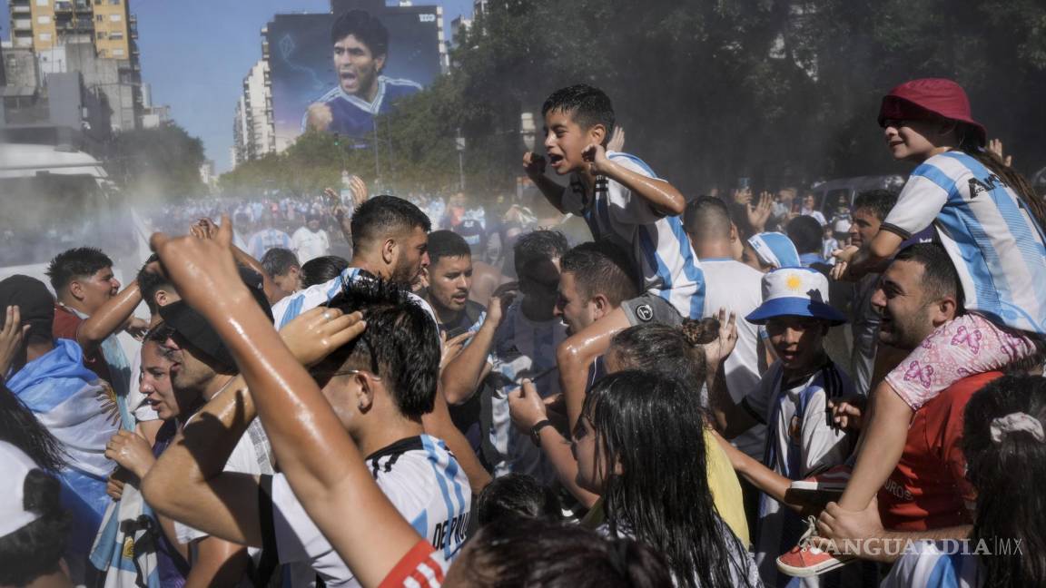 $!Fanáticos del fútbol que esperan para ver a la selección de fútbol de Argentina que ganó la Copa del Mundo son rociados con agua en Buenos Aires, Argentina.