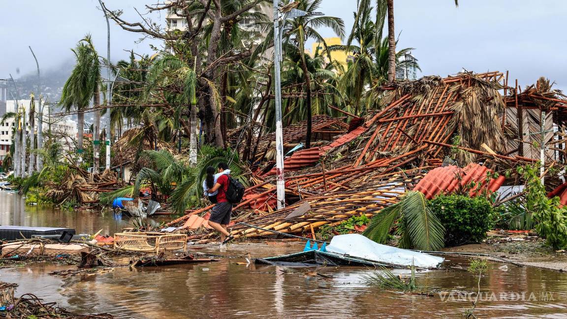 $!Un hombre sostiene a una niña mientras camina por una calle afectada por el paso del huracán Otis en el balneario de Acapulco, en el estado de Guerrero, México.
